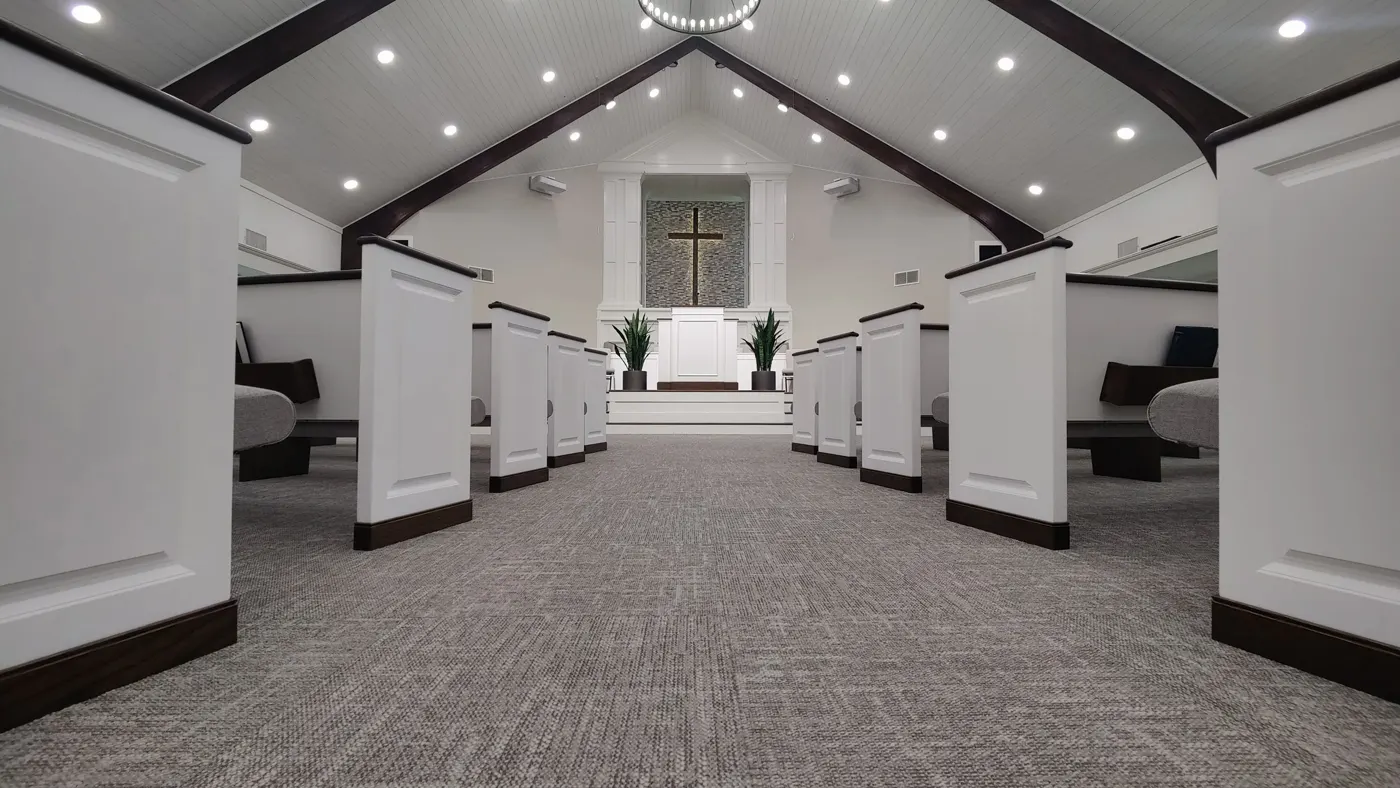 The Fairpark Baptist sanctuary, with white pews and a cross above the pulpit